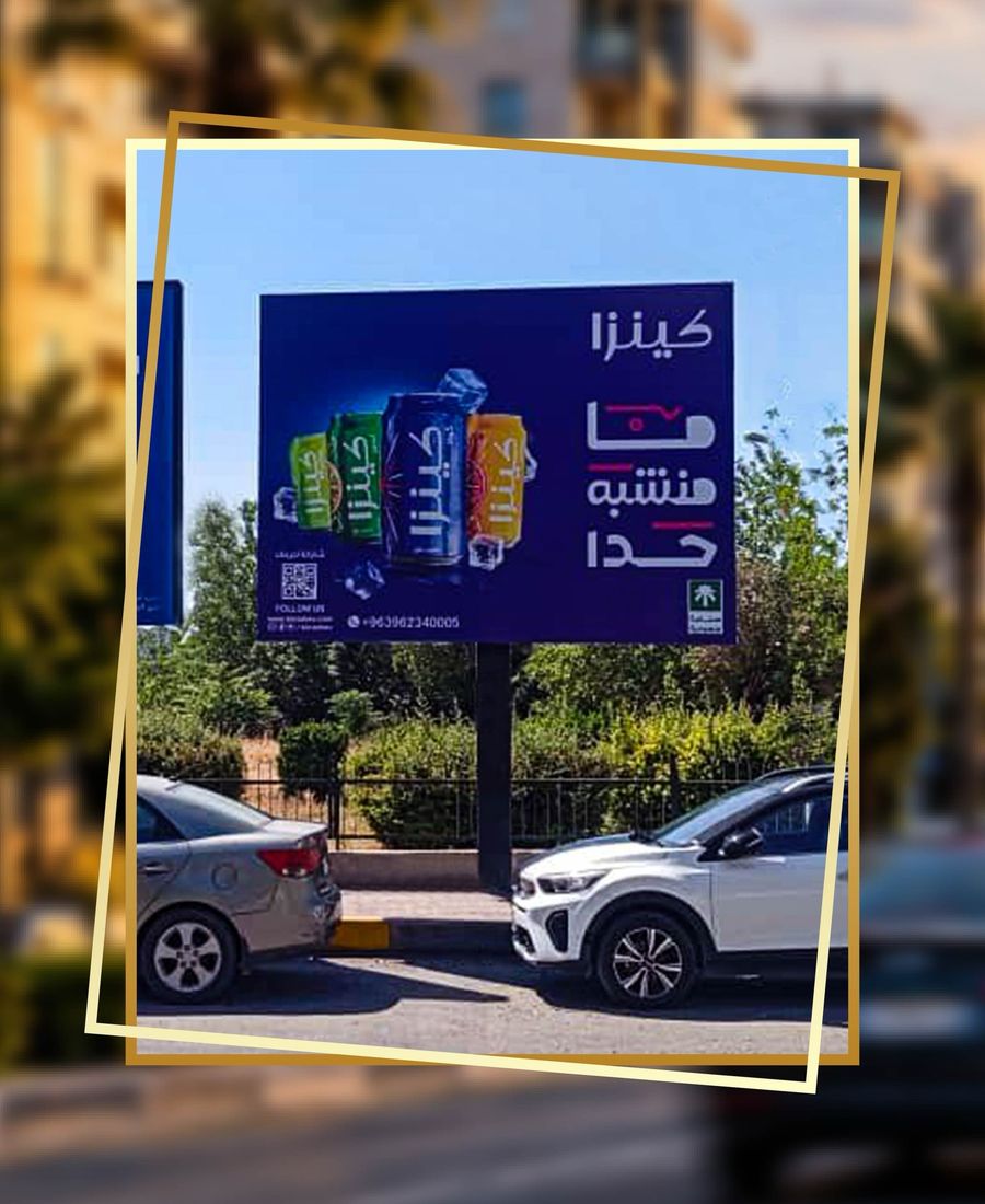 Kinza drinks billboard on a column, parked cars and a clipped hedge beneath the face